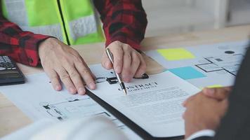 costruzione e struttura concetto di ingegnere o architetto incontro per progetto Lavorando con compagno e ingegneria utensili su modello edificio e planimetria nel Lavorando luogo, contrarre per tutti e due aziende. video