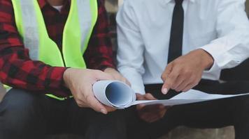 concepto de construcción y estructura de reunión de ingenieros o arquitectos para el proyecto que trabaja con socios y herramientas de ingeniería en la construcción de modelos y planos en el lugar de trabajo, contrato para ambas empresas. video