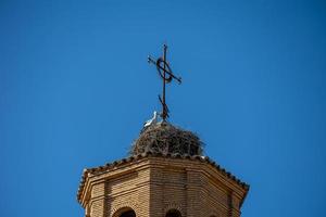 stork nest on the church tower against a blue sky with birds photo