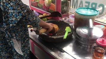 old mother's hand serving Rujak Buah, kacang lotis, or Indonesian fruit salad in a stone mortar, served with spicy brown sugar and peanut sauce video