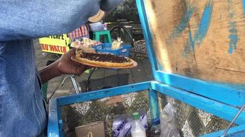 Selective focus. A man makes moonlit cakes. Made from wheat flour, sprinkled with powdered sugar or cocoa granules. Sweet or savory taste. Yogyakarta's old food video