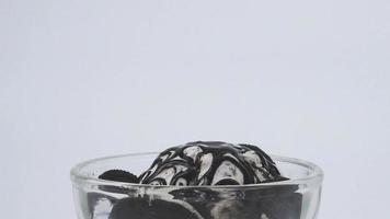 Front view of ice cream in a clear glass cup topped with chocolate sauce. video