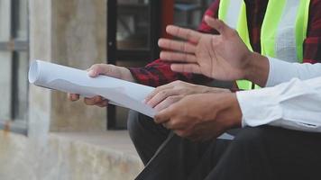 costruzione e struttura concetto di ingegnere o architetto incontro per progetto Lavorando con compagno e ingegneria utensili su modello edificio e planimetria nel Lavorando luogo, contrarre per tutti e due aziende. video