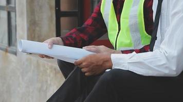 costruzione e struttura concetto di ingegnere o architetto incontro per progetto Lavorando con compagno e ingegneria utensili su modello edificio e planimetria nel Lavorando luogo, contrarre per tutti e due aziende. video