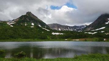 rotsachtig bergen en meer, wolken afdrijven aan de overkant lucht Aan bewolkt weer video