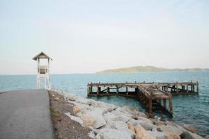 White Lifeguard tower and old wooden bridge with Seascape view on the beach in Thailand photo