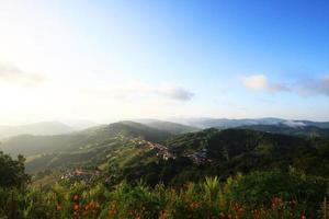 Aerial view Hill tribe village and Tea Plantation in sunrise on the mountain and forest is very beautiful flowers meadow in Chiangrai Province, Thailand photo