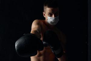 Boxer en un médico máscara y boxeo guantes en un negro antecedentes Copiar espacio foto