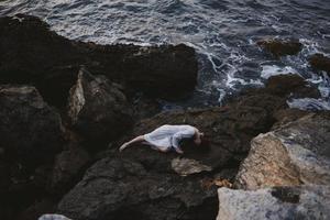 sensual woman lying on rocky coast with cracks on rocky surface view from above photo