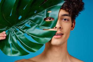 Cheerful guy with curly hair green leaf close-up clean skin photo