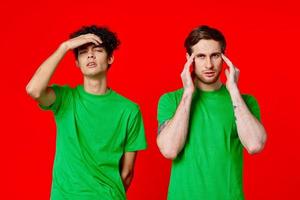 two men holding their heads in green T-shirts on a red background photo