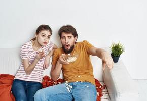 hombre con platos palomitas de maiz y mujer en naranja tartán sofá familia amigos teniendo divertido foto