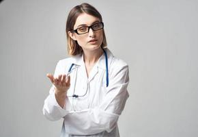 doctor with a stethoscope shows his hand to the side on a gray background Copy Space photo