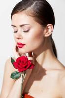Girl with bare shoulders Eyes closed with a rose in her hands body care photo