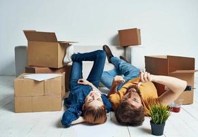 Moving to an apartment a man and a woman lie on the floor and a flower in a pot photo