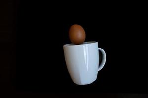 eggs falling into a white cup on a black background easter photo