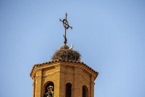 stork nest on the church tower against a blue sky with birds photo