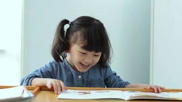 pequeño asiático niña es leyendo un historia libro.educación y colegio concepto. video