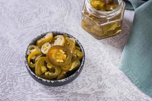 Spicy mexican pickled jalapeno peppers in bowl and glass jar photo