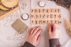Female hands lay out homemade cardboard runes in rows on the table top view photo