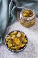 Spicy mexican pickled jalapeno peppers in bowl and glass jar vertical view photo