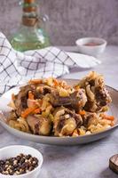 Stewed oxtail with carrots and onions on a plate on the table vertical view photo