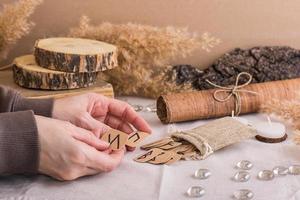 Women's hands are sorting through the Scandinavian divination runes on the table photo