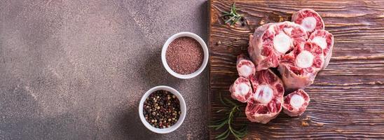 Pieces of raw oxtail and spices for cooking on a wooden board on the table top view web banner photo