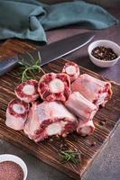 Pieces of raw oxtail and spices for cooking on a wooden board on the table vertical view photo