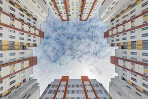 view up from ground to blue sky among skyscrapers, look at house from bottom up photo