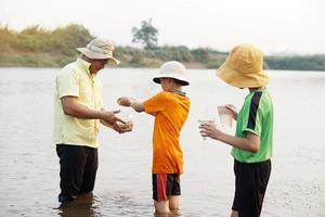 Asian man teacher and students are exploring water from nature source. Concept, Ecology and environment study. Outdoor summer camp activity. Education. Learning by doing. Life experience. photo