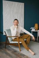 Young man sits lama in a cozy chair and looks at the camera photo