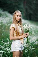 Cute young woman collects white wildflowers photo