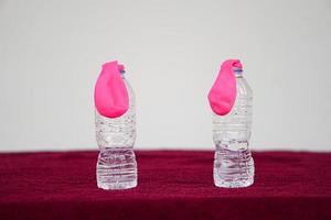 Pink flat balloons on top of transparent test bottles. Concept, science experiment about reaction of chemical substance, vinegar and baking soda that cause balloon inflat.  First  step of experiment photo