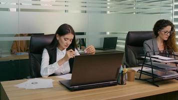 stressato donna Filatura il sedia mentre seduta a sua Lavorando posto nel ufficio. video