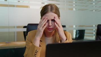 caucásico mujer de negocios sufrimiento desde dolor de cabeza debido a computadora trabajo excesivo. video