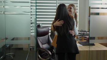 Back view of woman entering the office after a business journey hugs a coworker. video