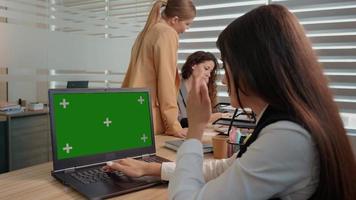 Businessman working on a laptop with green screen on background colleague discussing details. video