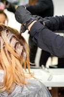 Hairdresser coloring hair of woman photo