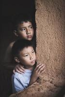 Closeuptwo poor children peeking out of a dilapidated house, Concept of assistance to the poor, human rights, violence against children. photo