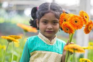 Bangladesh diciembre 07, 2017 retrato de un niño participación algunos gerbera flores en un gerbera flor jardín a sabar, dhaka. foto