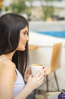 el lado ver de un joven mujer Bebiendo café descansando a el recurso a un café al aire libre. foto