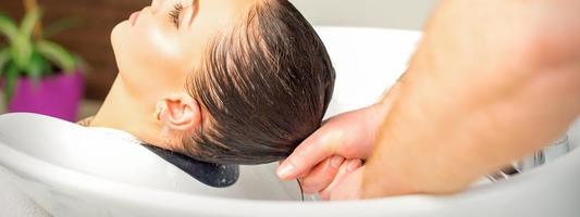 Hairdresser washing hair of client photo