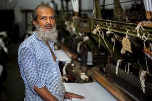 Bangladesh August 05, 2019 A yarn factory worker has made white cotton cloth in the machine at Narsingdi, Bangladesh. photo