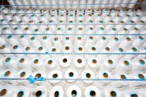 Top view of A lot of white yarn spools in a textile factory. White yarn spools in a clothing factory. photo