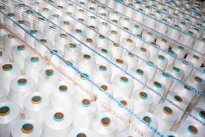 Top view of A lot of white yarn spools in a textile factory. White yarn spools in a clothing factory. photo