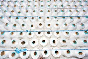 Top view of A lot of white yarn spools in a textile factory. White yarn spools in a clothing factory. photo