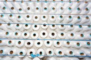 Top view of A lot of white yarn spools in a textile factory. White yarn spools in a clothing factory. photo
