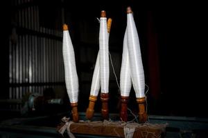 White yarn spools close-up in a yarn factory. White yarn spools in dark background. photo