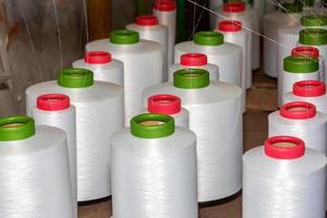 Red-green spools of white yarn in a garment factory. Weaving loom in a textile factory. photo